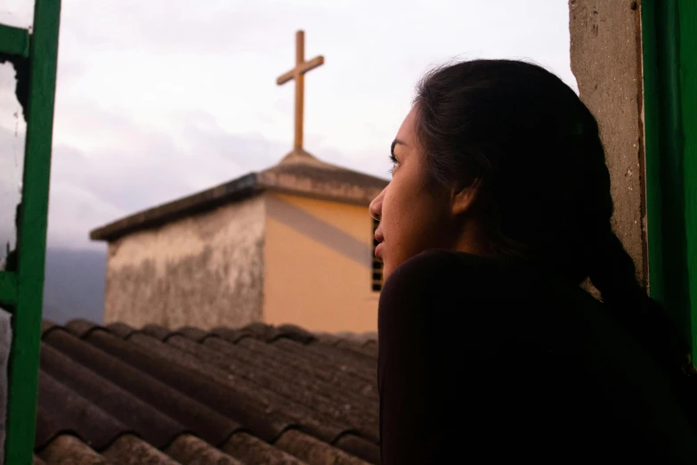 a woman is staring at the sky while standing next to a building