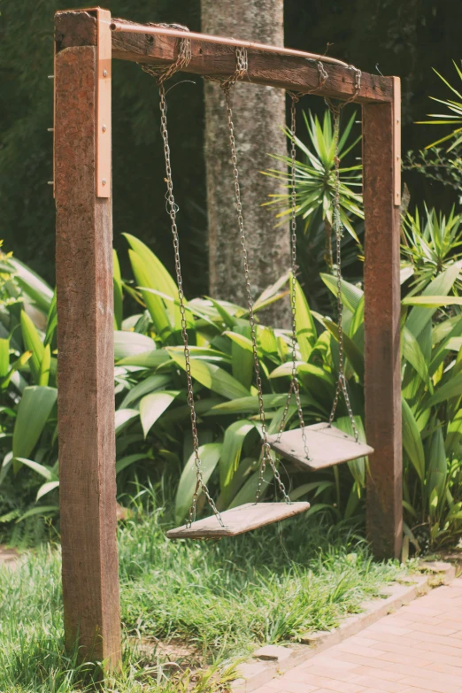 a swing frame in the ground near some plants