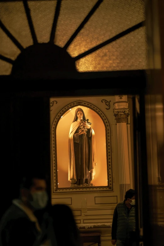 a statue in a room with people looking on