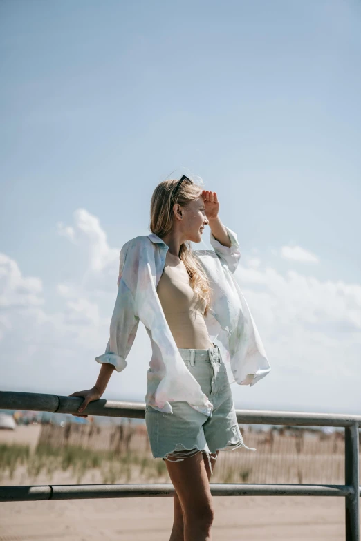 young lady standing on beach fence overlooking ocean