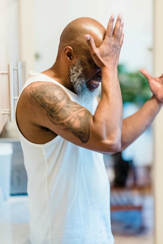 man standing in the kitchen holding his hand up while making the okay gesture