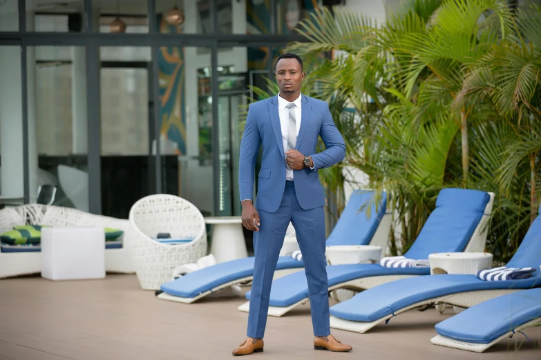 a man in a suit stands next to blue chairs