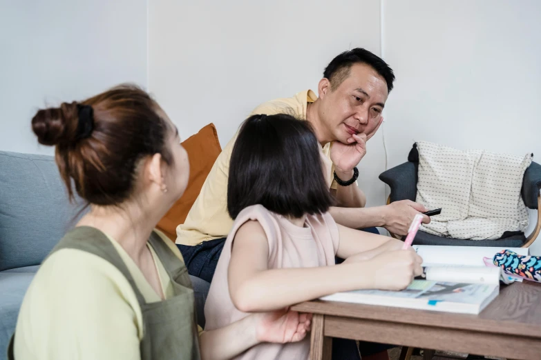 a man sitting on a couch with two young women watching him