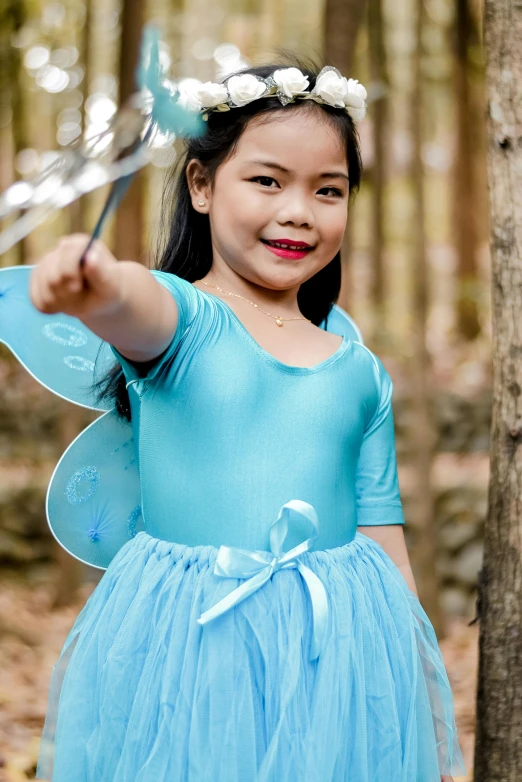 a little girl holding up an umbrella near some trees