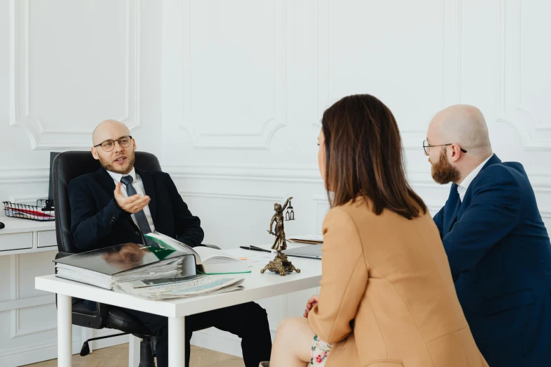 three people sitting at a white table in front of a computer screen