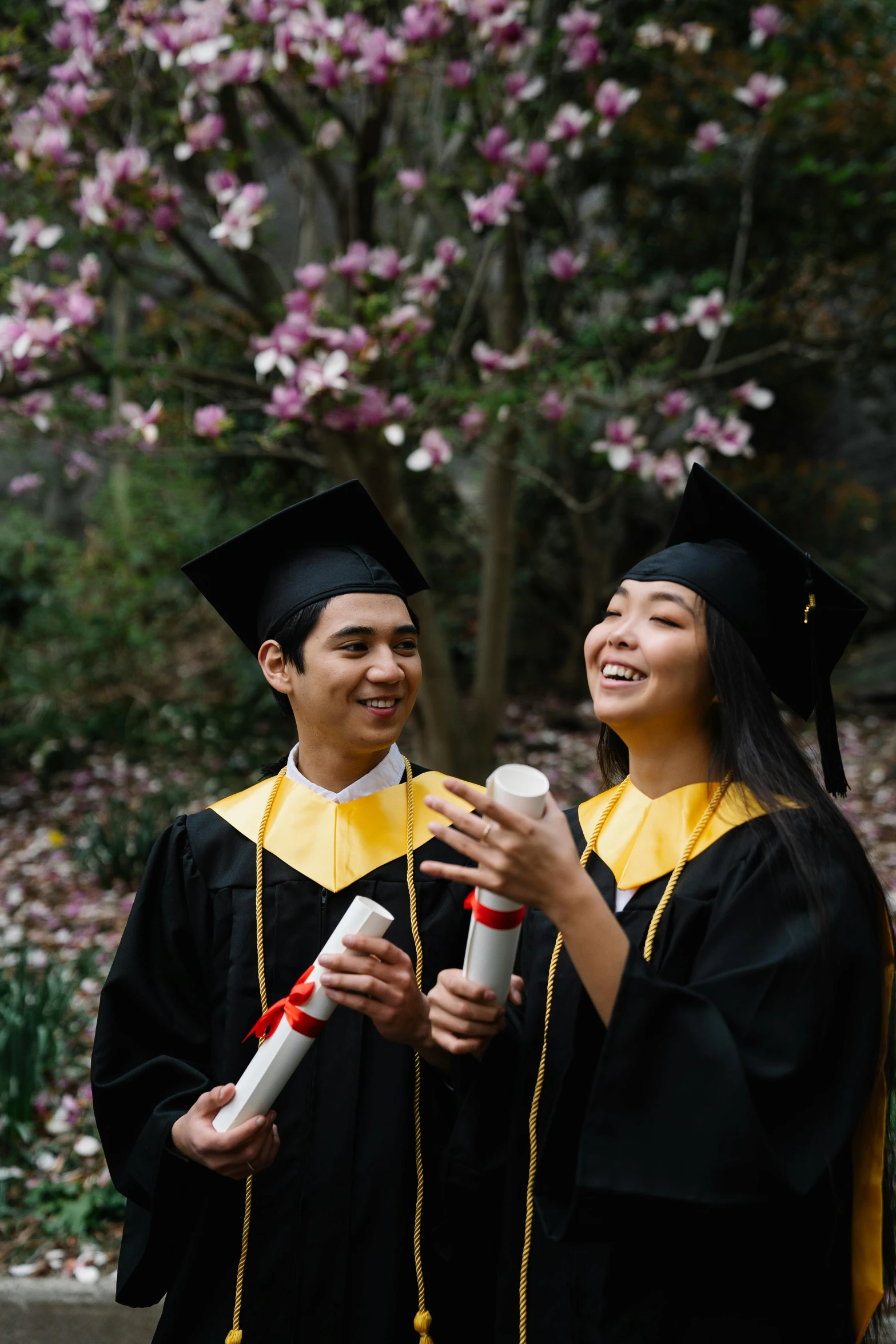 two graduate smiling and wearing graduation robes