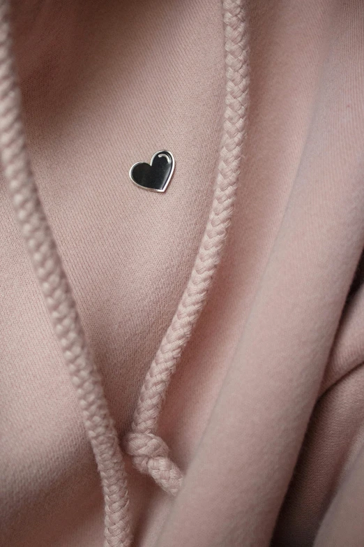 close up of a cardigan sweater with an enamel heart on the front