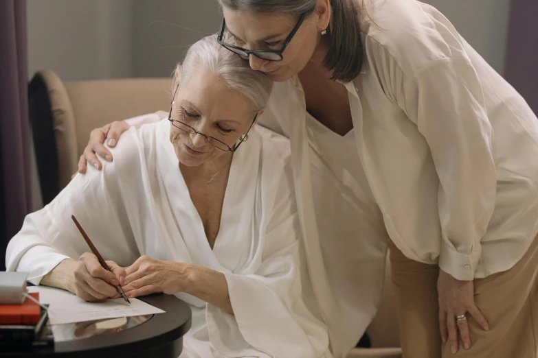 a woman helping a younger woman with her writing