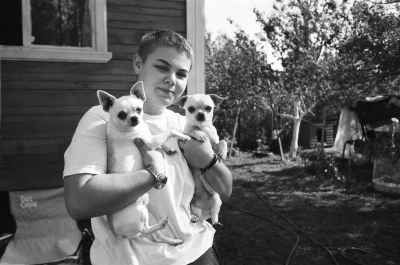 a man holds three baby chihuahuas while outside a house