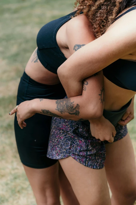 two women hugging while wearing swimsuits in an open field