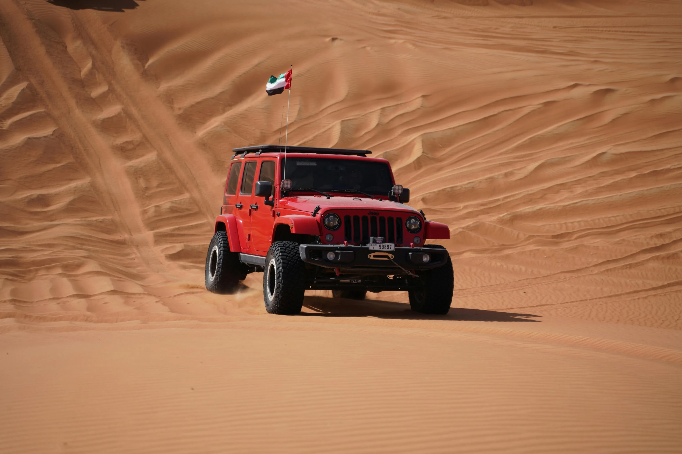 a jeep drives in the desert with a flag