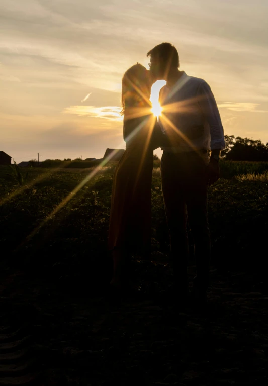 the man and woman are kissing each other in a field