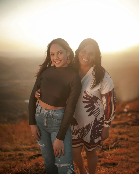 two women standing on the top of a hill