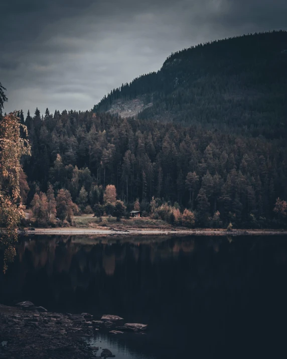 the mountain landscape is dark and cloudy over the water