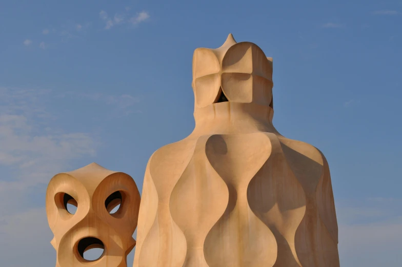 a wooden sculpture near another sculpture in the background