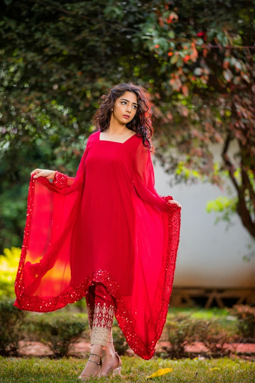 a woman with dark hair is wearing a red dress