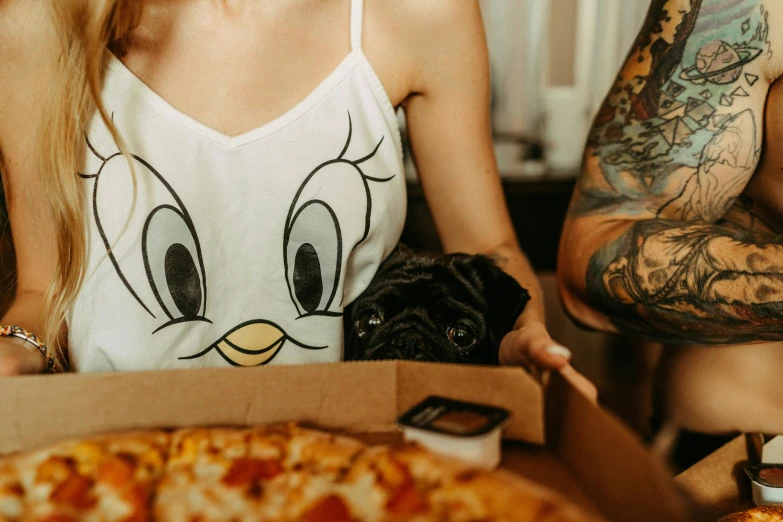 a girl and guy are sitting together by the pizza