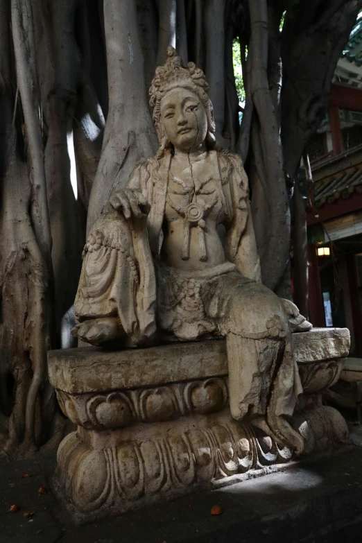 a stone statue is placed between large, bare trees