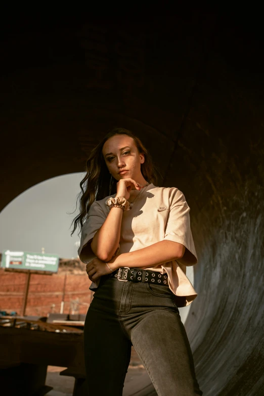 the girl is posing in front of an overpass