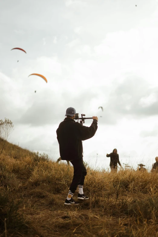 a man flying a kite while standing on top of a hill