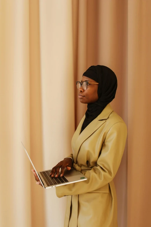 a woman in a tan jacket using a laptop