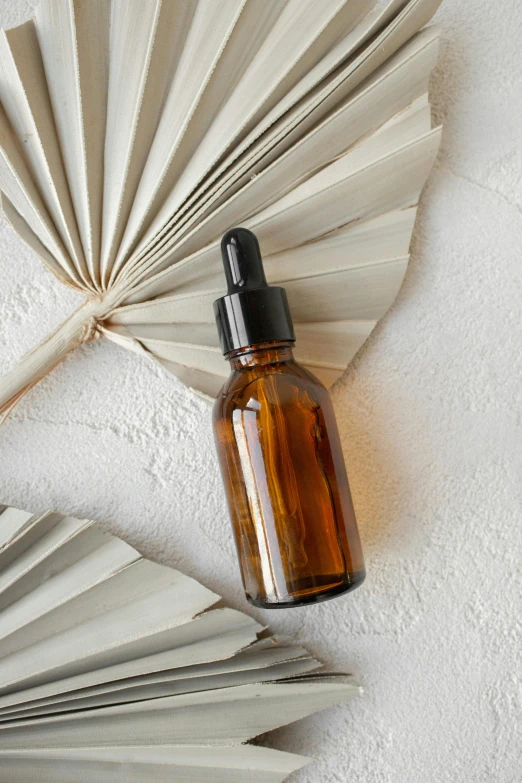 an open glass bottle with a black top sitting on the wall next to a fan