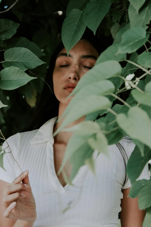 woman with eyes closed holding onto the leaves of her plant