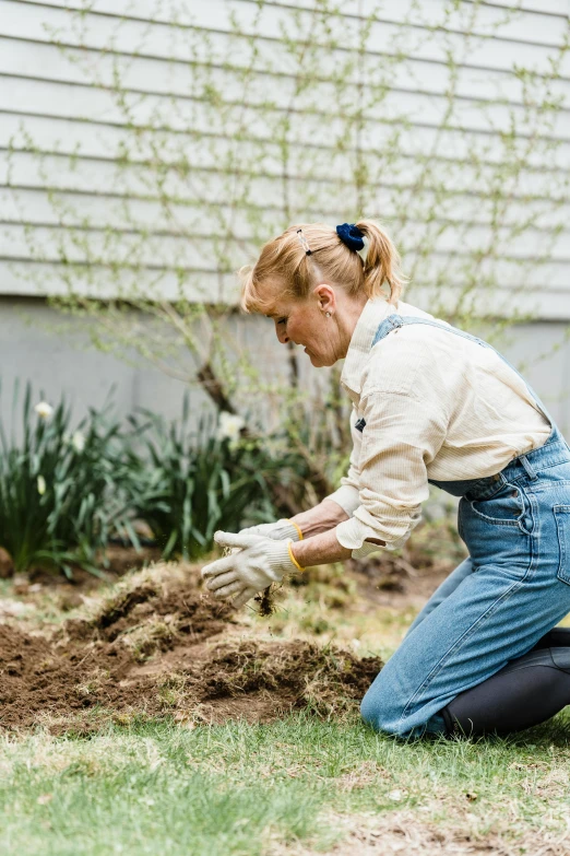 woman in blue jean work on yard digging grass