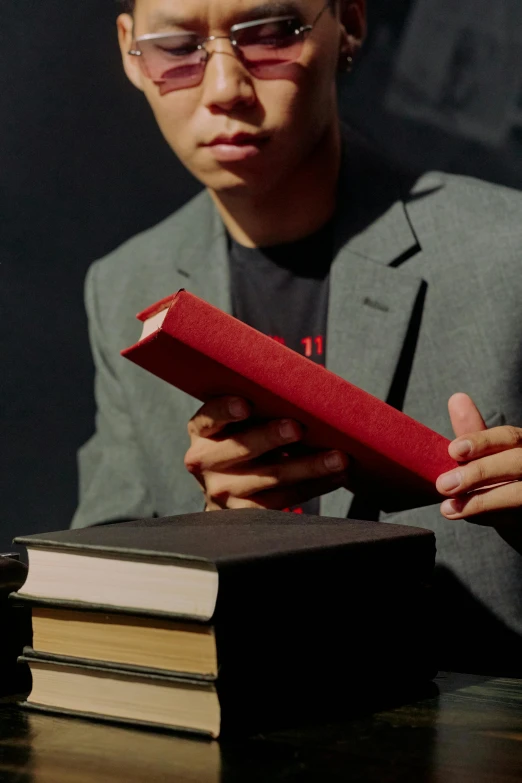 a man in a suit looks at a book on a table