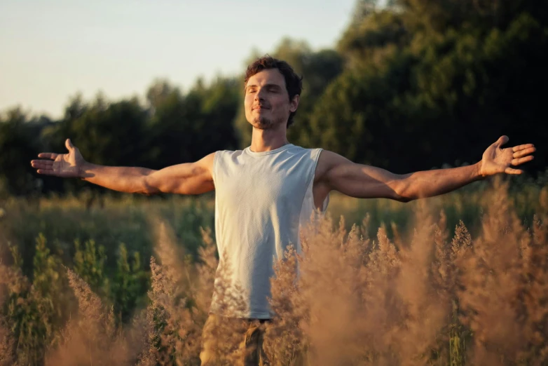 a man standing in tall grass holding his hands out