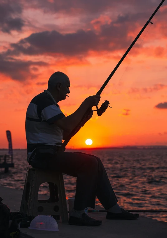 man fishing on the beach during sunset while sitting
