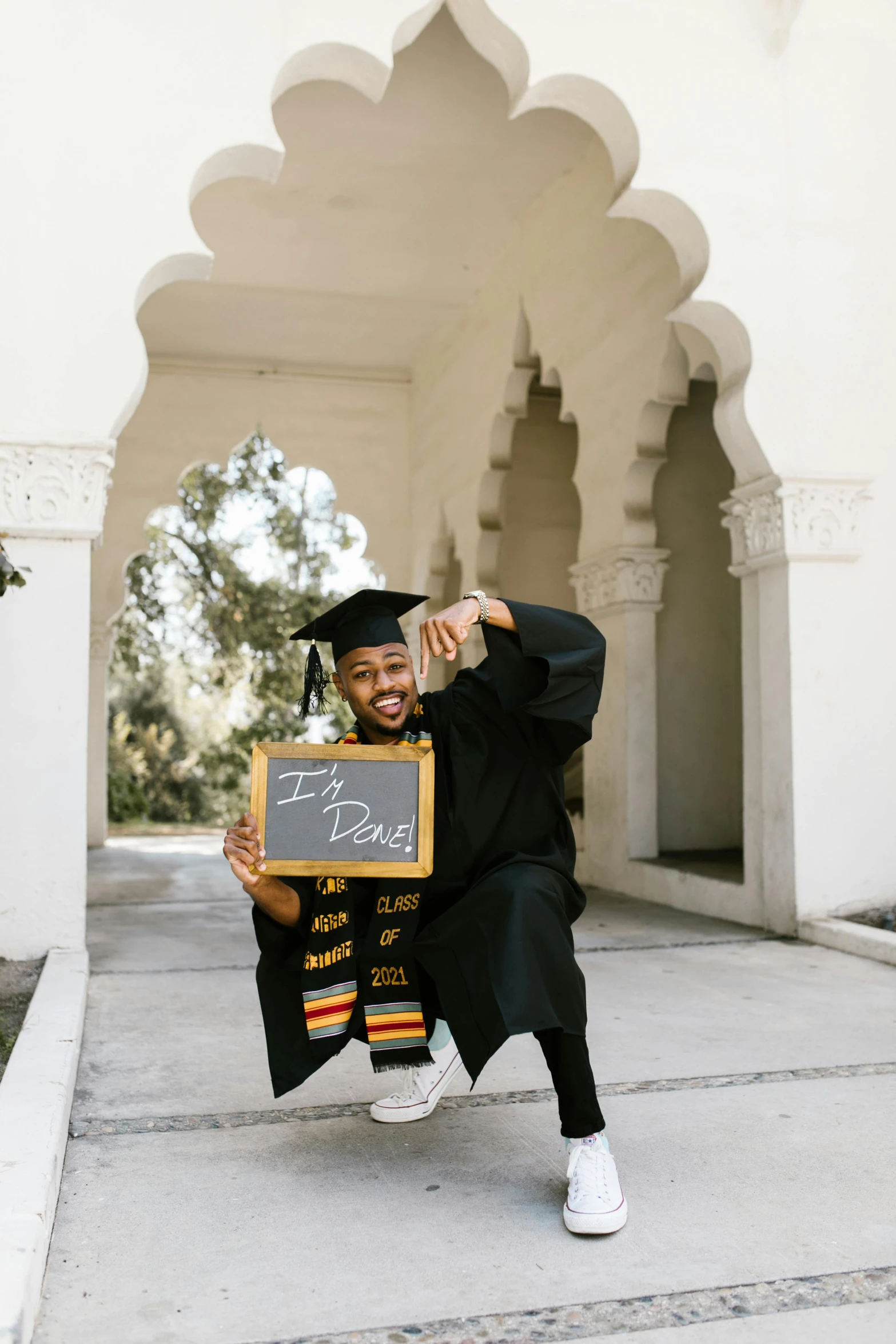 a person in graduation gown holds up a chalkboard