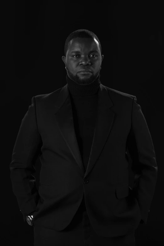 black man in black suit looking at the camera