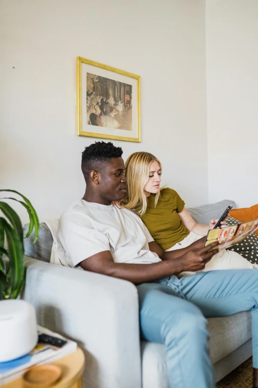 a man and a woman sitting on the couch reading books