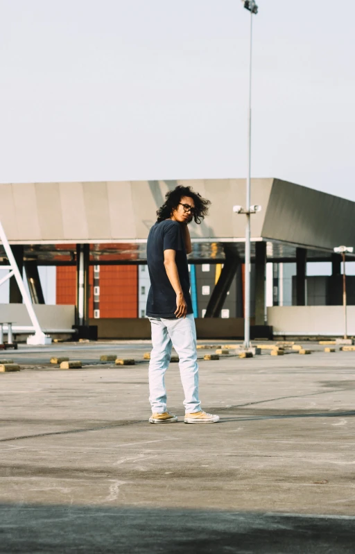 a young man is standing in the parking lot, looking to his right