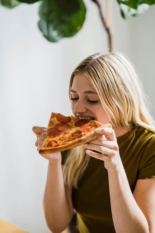 a woman eating a slice of pizza on top of a wooden table