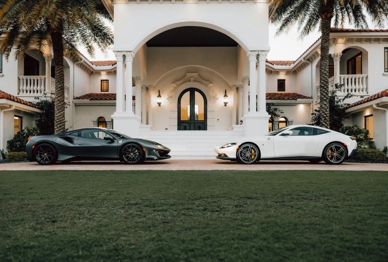 two sports cars are parked in front of a house