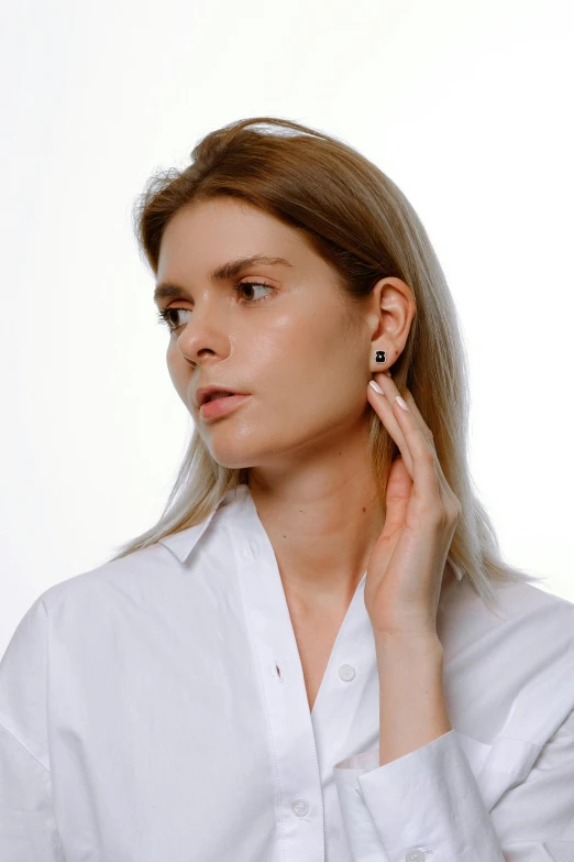 a woman wearing white shirt and ear ring with diamond detail