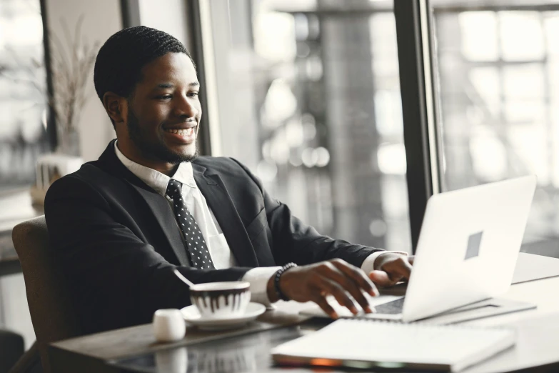 the man sits at his desk using a laptop