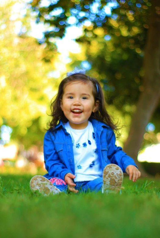 a little girl sitting in the grass with some grass around her