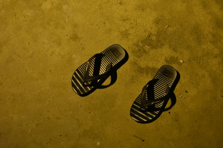 one pair of flip flops with a broken one lying in the street