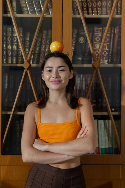 a woman posing with a fruit on her head