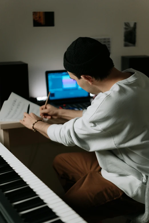 a person sitting at a piano writing on a paper