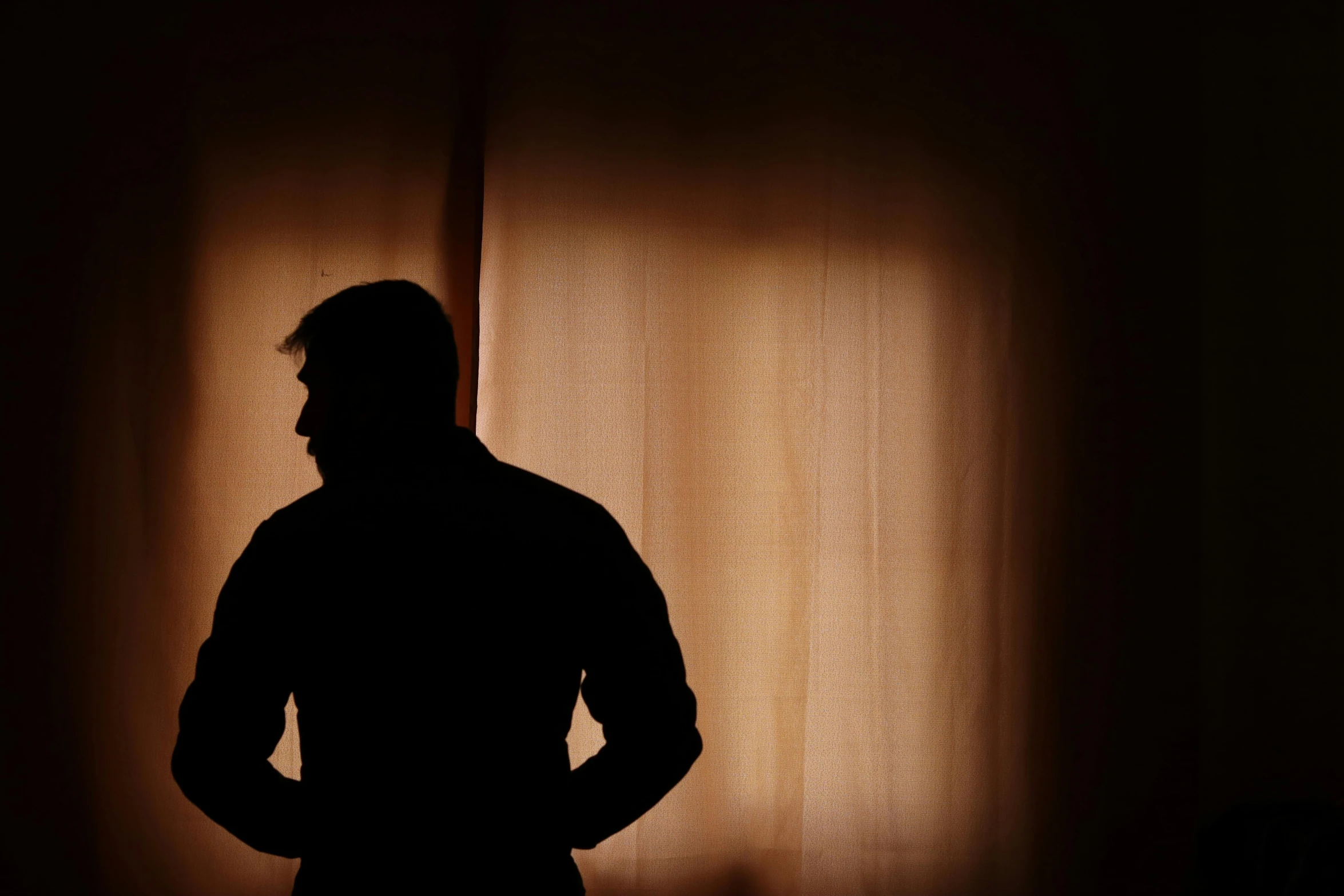 a silhouette of a man standing against a curtain