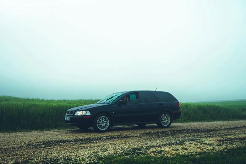 a car is driving on a dirt road in the middle of a field