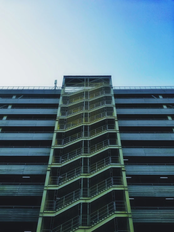 a tall green and metal building with stairs going up