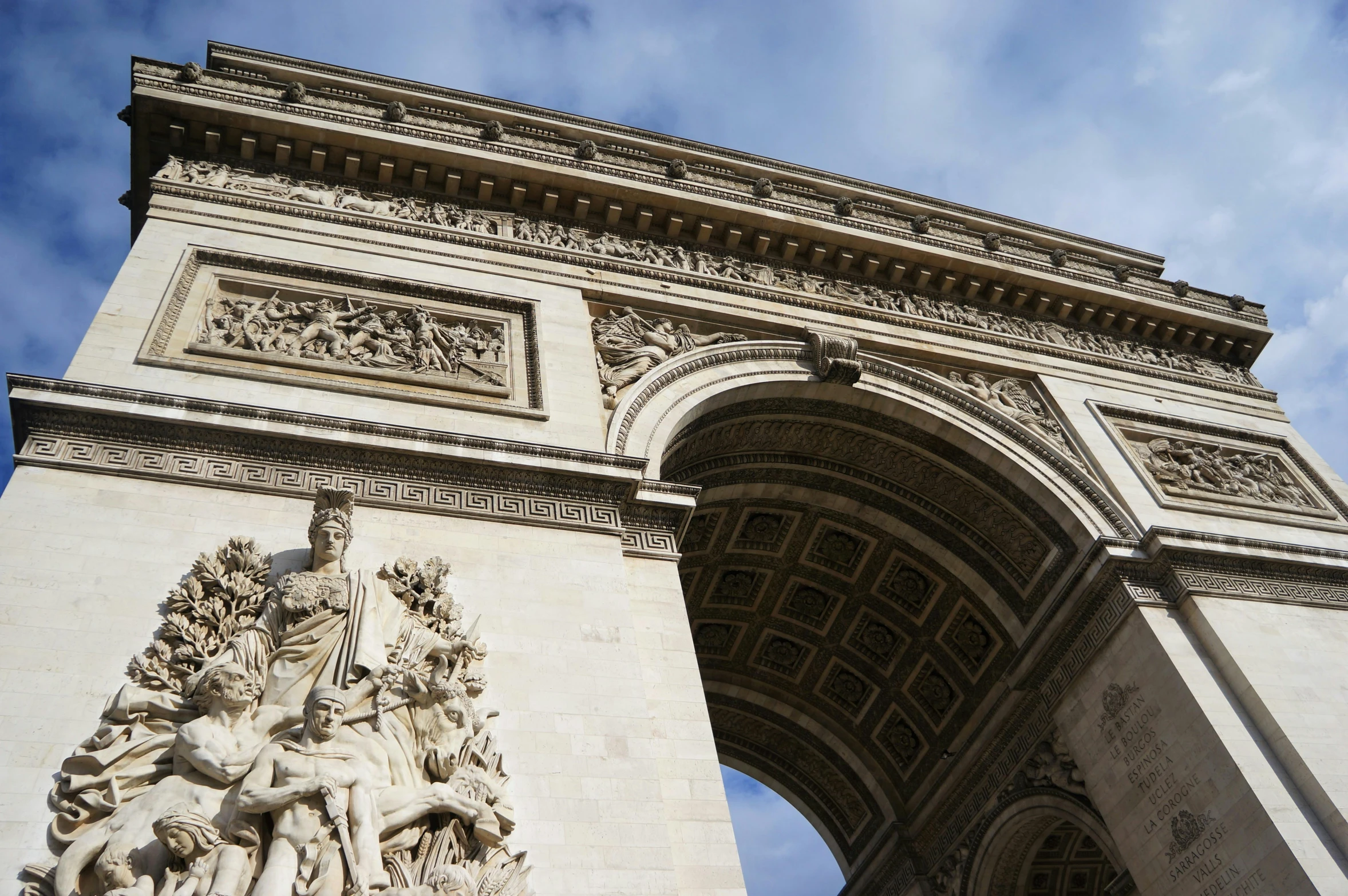 a stone arch with statues on it under a cloudy sky