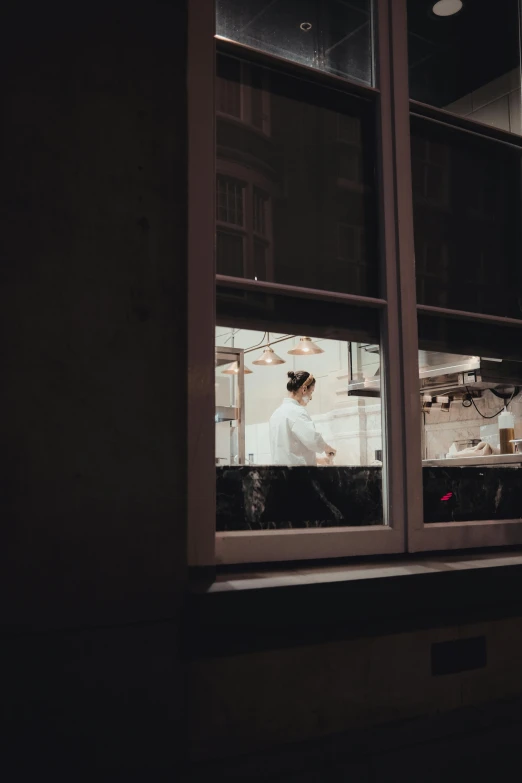 people cooking in a kitchen with open windows at night