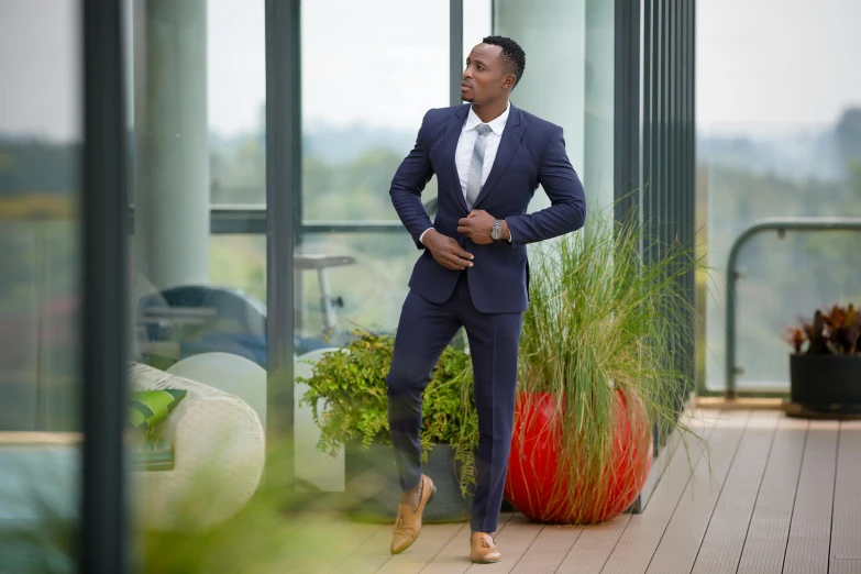 a man in a suit posing near some plants