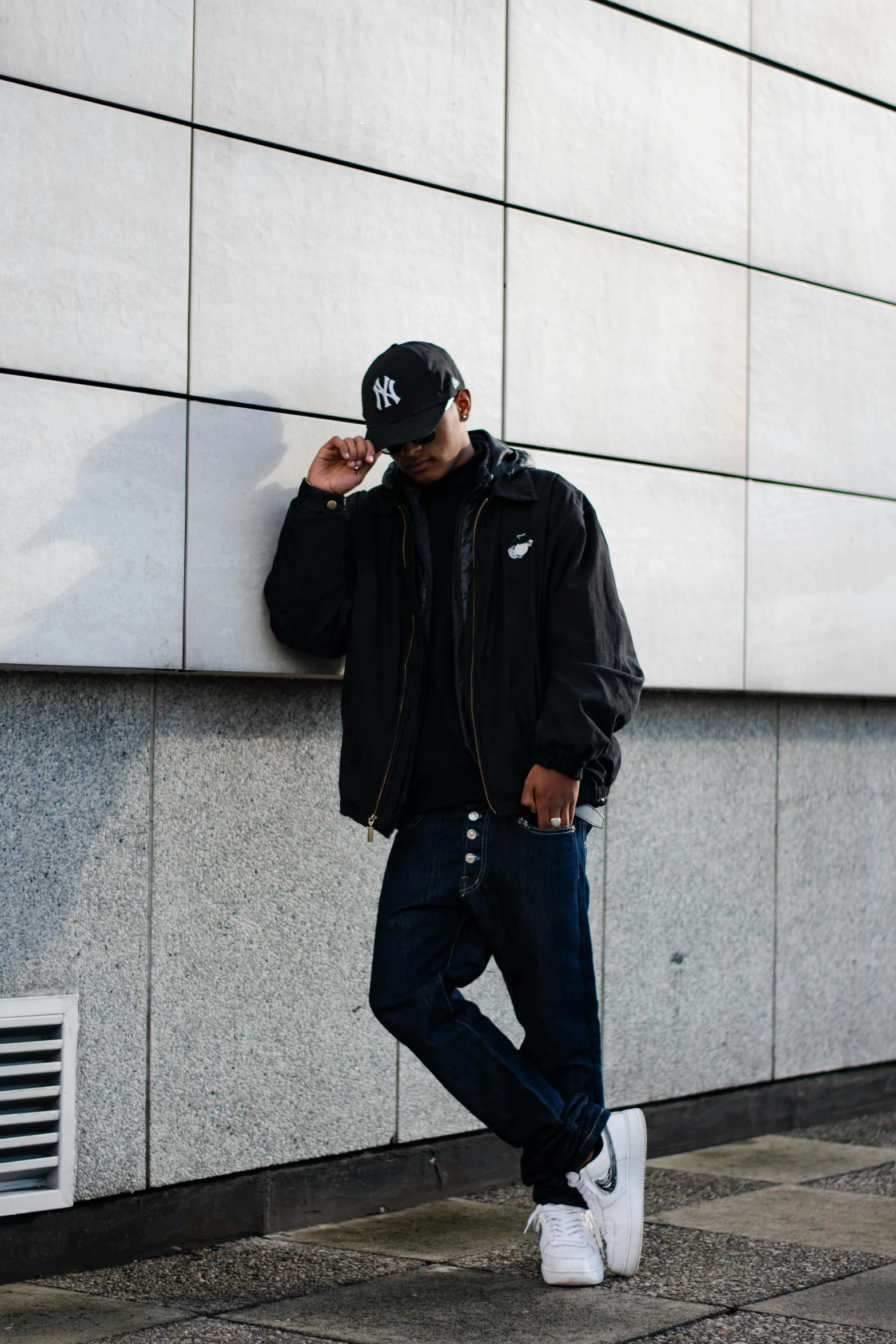 a man leaning up against a wall talking on his cellphone